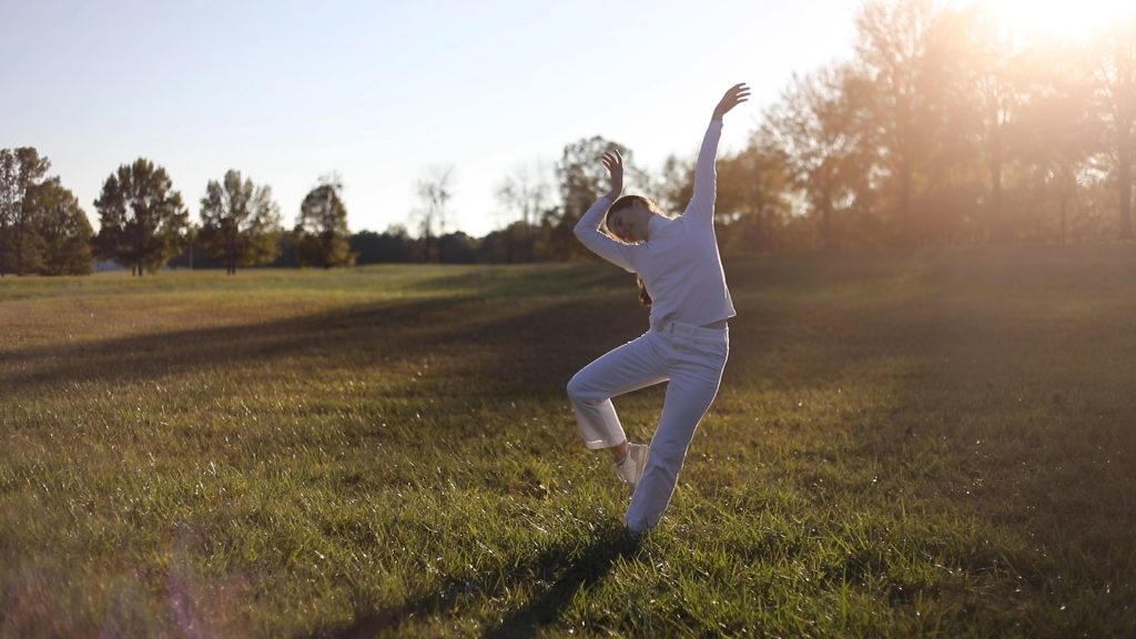 A dancer in white in the center of a field.