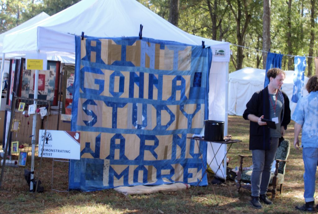 A quilt on display reads: Ain't Gonna Study War No More.