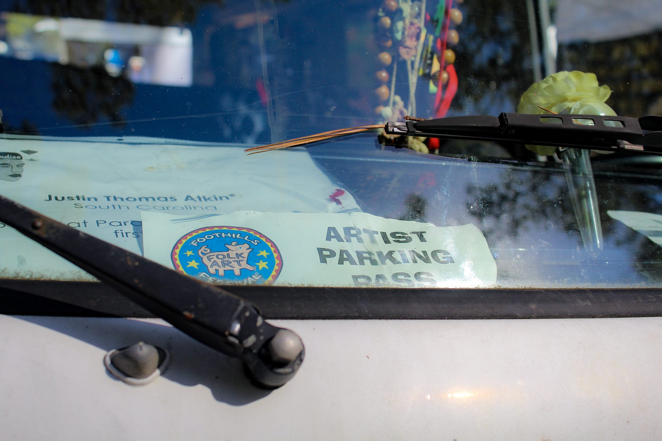 A parked car displays a badge: Artist Parking Pass.