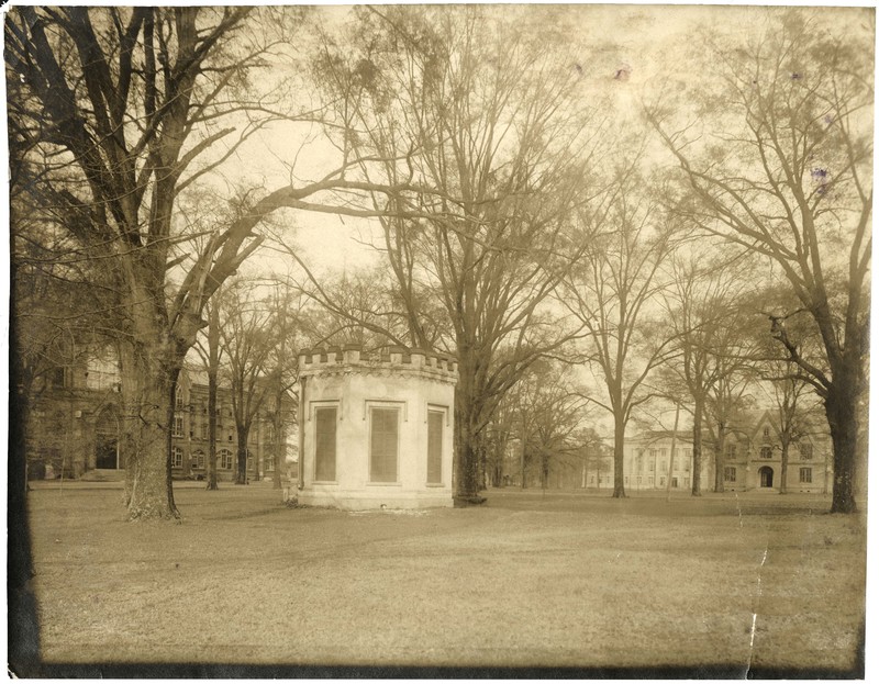 A photograph of a small round building in the middle of a lawn with some trees.